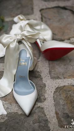 a pair of white high heeled shoes sitting on top of a cobblestone floor