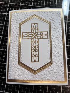 a white and gold card with a cross in the center on it's side