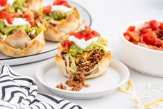 some taco shells are sitting on plates with other dishes in the backgroud