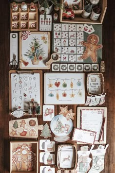 a collection of christmas cards and other items laid out on a wooden table with pine branches