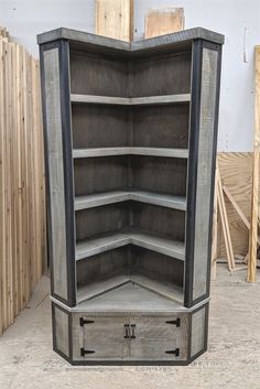 an empty wooden storage cabinet in a room filled with wood planks and other pieces of furniture