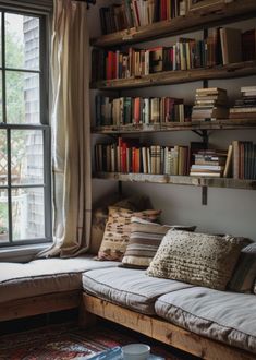 a living room filled with lots of books next to a window