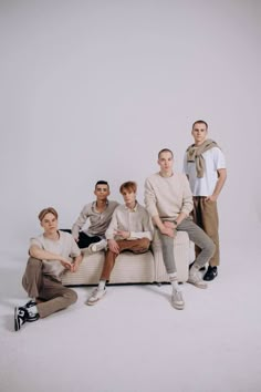 five men are sitting on a couch posing for a group photo in front of a white background