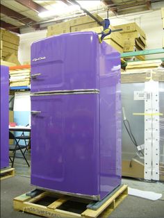 a purple refrigerator sitting on top of a wooden pallet in a room filled with boxes