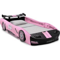 a pink and black race car bed with wheels on the bottom, in front of a white background