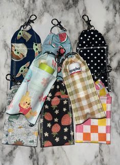 six baby bibs are lined up on a marble counter top, one has a bottle in it and the other has an oven mitt