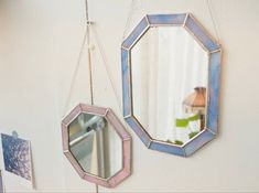 two mirrors hanging on the wall next to each other