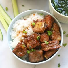 a bowl filled with meat and rice next to vegetables