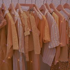 there are many different colored shirts hanging on the clothes rack in front of some glittery wallpaper