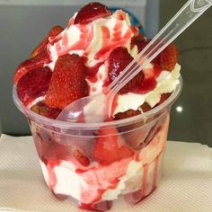 a plastic cup filled with strawberries and whipped cream