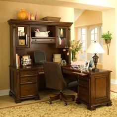 a home office with desk, chair and hutch in an empty living room area