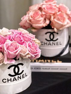 two buckets filled with pink roses sitting on top of a table