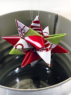 red and white origami stars hanging from a silver pot with water in it