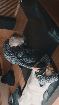 two people standing next to each other in a room with wood floors and black furniture