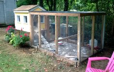 a chicken coop in the yard with a pink lawn chair next to it