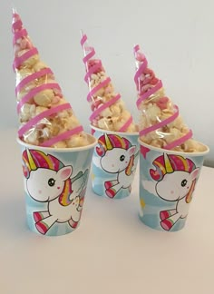 three cups filled with candy and topped with unicorns