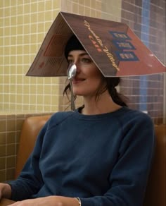 a woman sitting in a booth with a paper hat on her head