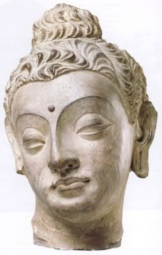 the head of a buddha statue with its eyes closed and one eye closed, is shown