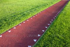 a long red path with white arrows on it in the grass - stock photo - images