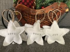 three white star ornaments sitting on top of a couch next to a basket filled with greenery