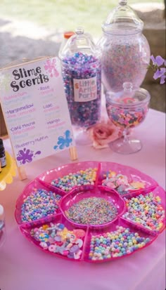 a table topped with lots of candy and confetti on top of pink plates