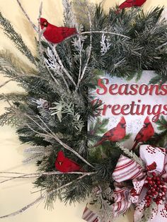 a christmas wreath with red birds on it and the words season's greetings