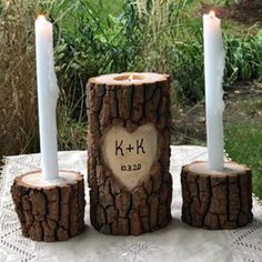 three candles are placed in the shape of logs with a heart on one candle holder