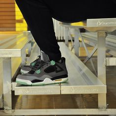 a person is standing on a bench with their feet up and wearing black pants, green sneakers