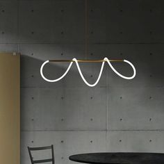 a black table and chair in front of a wall with three lights hanging from it