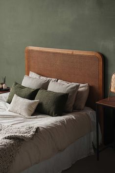 a bedroom with green walls and white bedding, two nightstands on either side