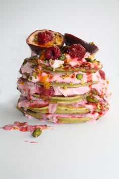 a stack of pancakes with fruit and whipped cream on top, topped with pistachio