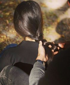 a woman sitting on the ground tying her hair