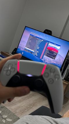 a person holding a video game controller in front of a computer screen with the tv on