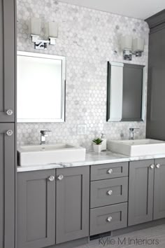 a bathroom with two sinks, mirrors and cabinets in grey color scheme on the wall