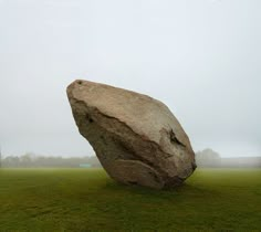 a large rock sitting on top of a lush green field