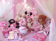 a group of stuffed animals sitting on top of a pink bed covered in white netting