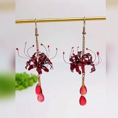 two pairs of earrings with red flowers hanging from them