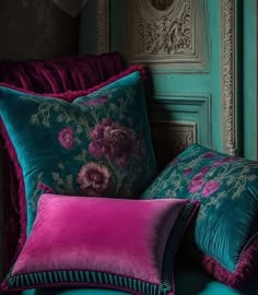 two pillows are sitting on a chair in front of a wall with ornate carvings and flowers