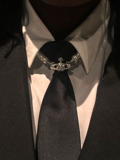 a man wearing a black tie and white shirt with a crown on it's lapel