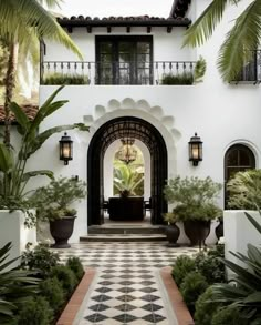 an entrance to a house with potted plants on either side and a checkered tile floor