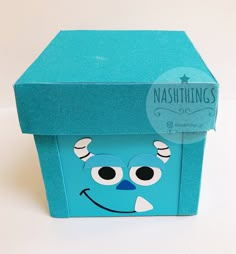 a blue box with a face painted on the front and sides, sitting on a white surface