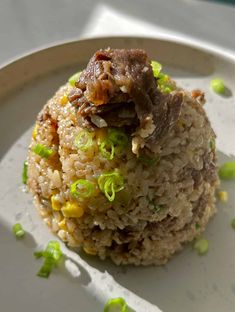 a white plate topped with rice covered in meat and veggies on top of it