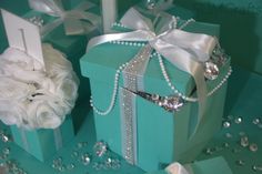 two blue boxes with pearls and ribbons on them, one has a flower in it