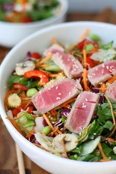 a white bowl filled with meat and veggies on top of a wooden table