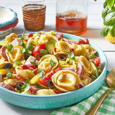 a bowl filled with pasta and vegetables on top of a table next to silverware