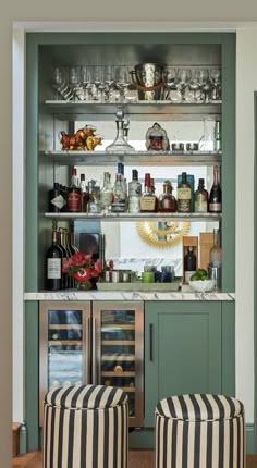 a bar with two stools in front of it and bottles on the shelves above