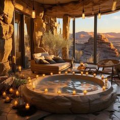 an outdoor hot tub surrounded by candles in the middle of a room with large windows