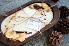 a wooden tray filled with white chocolate next to pine cones and twined twine