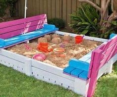 an outdoor sandbox made to look like a couch with pink and blue cushions on it