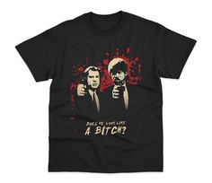 two men in black shirts with red paint splattered on them, one pointing at the